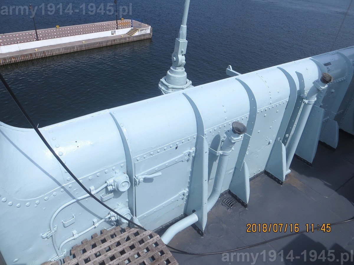 76. ORP Błyskawica, obudowa pomostu ma prawej burcie już za podestem pomostu dowodzenia. Na środku widoczne drzwiczki umożliwiające dostęp do zielonego światła pozycyjnego.  Na początku II wojny światowej na lewej stronie takiego zdjęcia zobaczylibyśmy podstawę palową z dwoma karabinami maszynowymi Levis a dalej po prawej stronie zdjęcia stół nawigacyjny z otwieraną brezentową osłoną. 