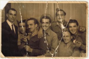 La fraternità non ha confini – Braterstwo nie zna granic. Pierwszy z prawej Emilio Pizzola. Na fotografii występuje m.in. Attilio Brunetti, dwóch żołnierzy jugosłowiańskich (jeden z nich to Josef Baranowa) oraz w ubraniu cywilnym Mitchel Tyndall. Zwraca uwagę noszenie przez żołnierzy 111. KOM beretów General Service Cap z polskimi orzełkami na zielonej podkładce w barwie commandosów oraz standartowych furażerek Field Service Cap. Widoczna jest również oznaka krzyżowców 8. Armii Brytyjskiej naszyta odmiennie na lewym przedramieniu poniżej naszywki POLAND. (fot. ze zbioru R. Pizzola)